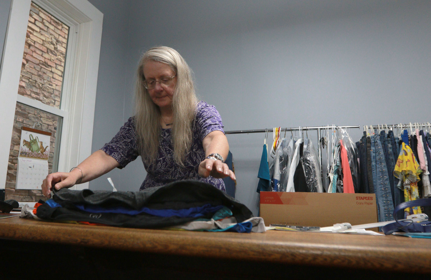 Gloria Benson, owner of Glad Rags Boutique, folds shirts inside the store in Stockton, Ill., on Friday, July 9, 2021.    PHOTO CREDIT: Katie Goodale