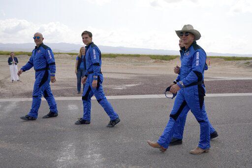 Mark Bezos, from left, Oliver Daemen, Wally Funk, right rear, and Jeff Bezos, founder of Amazon and space tourism company Blue Origin walk out to see the nearby rocket that landed safely after their launch from the spaceport near Van Horn, Texas, Tuesday, July 20, 2021. (AP Photo/Tony Gutierrez) PHOTO CREDIT: Tony Gutierrez