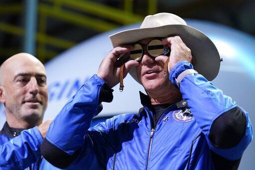 Mark Bezos, left, looks on as Jeff Bezos, founder of Amazon and space tourism company Blue Origin, puts goggles over his eyes that belonged to aviator Amelia Mary Earhart during a post launch news briefing from its spaceport near Van Horn, Texas, Tuesday, July 20, 2021. The goggles were carried aboard the New Shepard during Tuesday