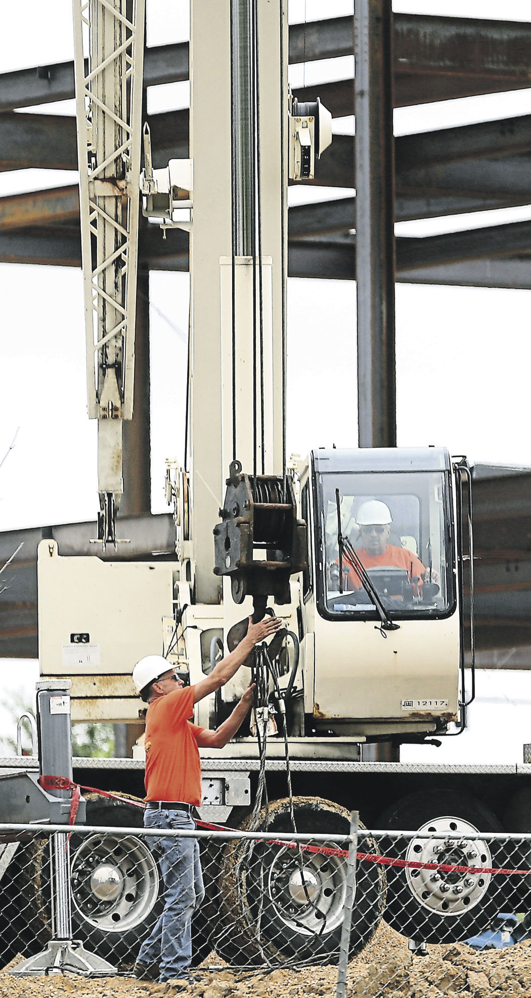 Peter Simon (right) operates a crane while Rod Maas, both with A-1 Crane Rental & Machinery Moving, helps maneuver an item at the construction site of the new Grand River Medical Group building along Westmark Drive in Dubuque.    PHOTO CREDIT: JESSICA REILLY