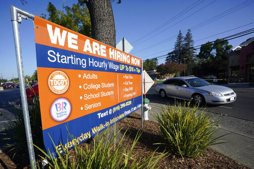 A car passes a hiring banner in Sacramento, Calif., Friday, July 16, 2021. Hiring in California slowed down in June 2021 as employers in the nation
