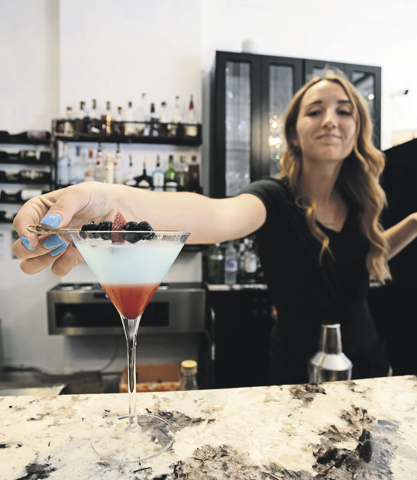 Bartender Addison Soat adds a garnish to a martini.    PHOTO CREDIT: SYSTEM