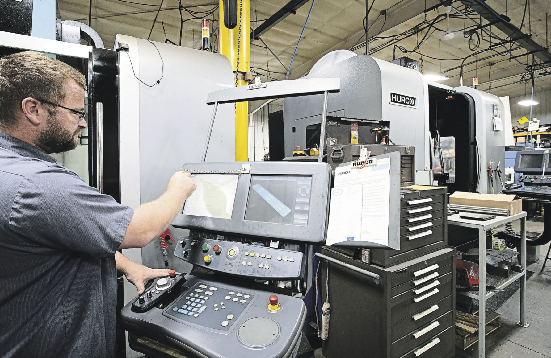 Eric Willenbring programs an automated milling machine at Rauen Precision Machining in Farley, Iowa.    PHOTO CREDIT: SYSTEM