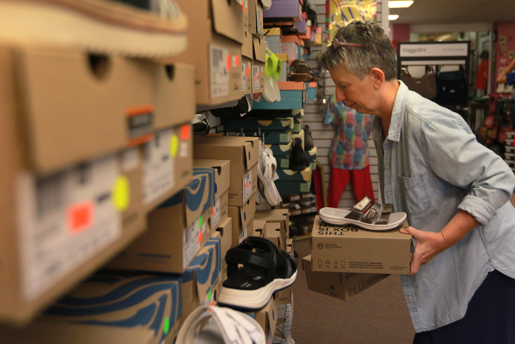 Deb May, of Dubuque, tidies the shoe display at HJ’s Fashion Emporium in Dubuque on Wednesday, Aug. 4, 2021. May has been an employee at the store for two years.    PHOTO CREDIT: Katie Goodale