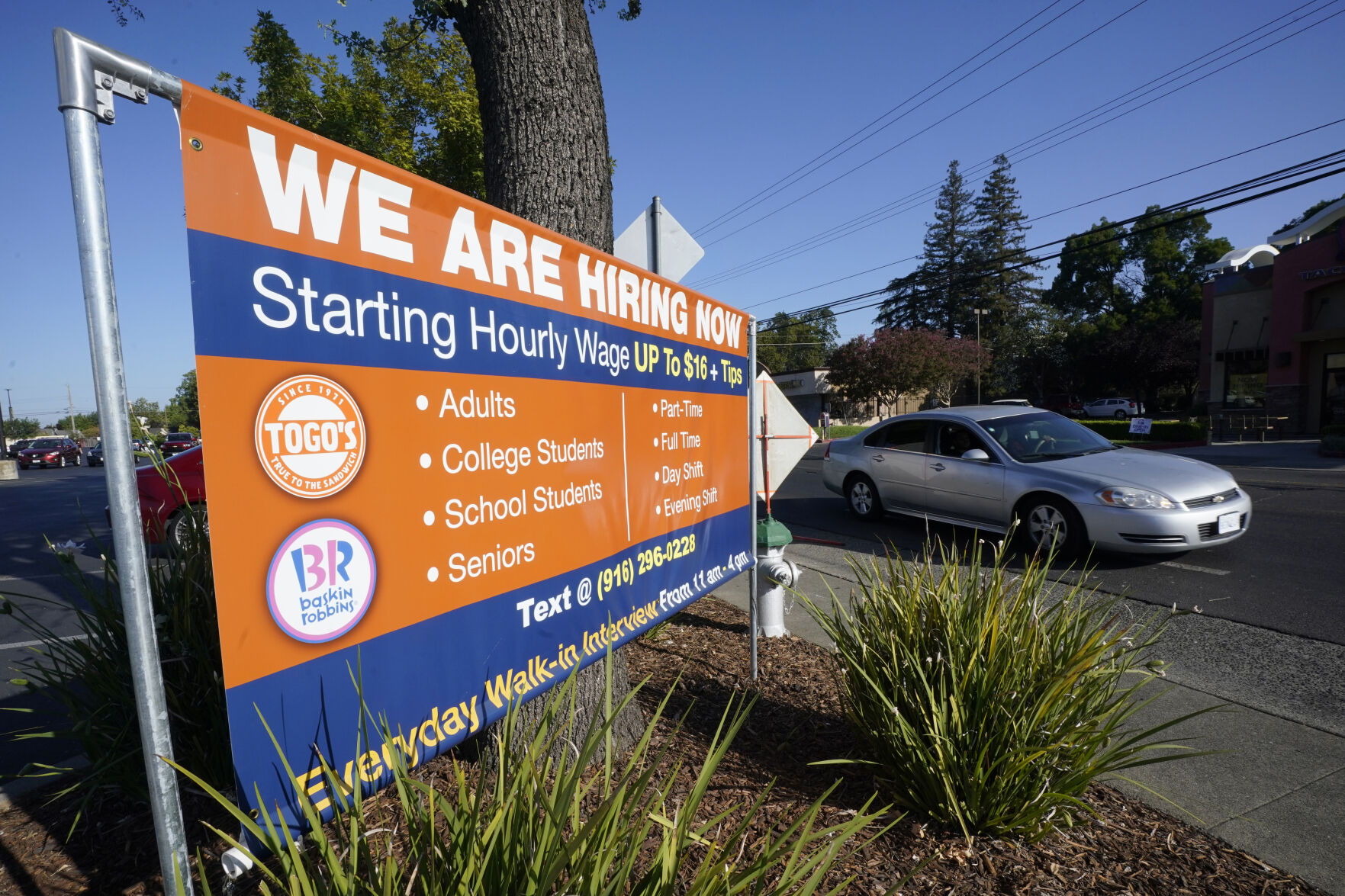 A car passes a hiring banner in Sacramento, Calif.. Hiring in California slowed down in June 2021 as employers in the nation