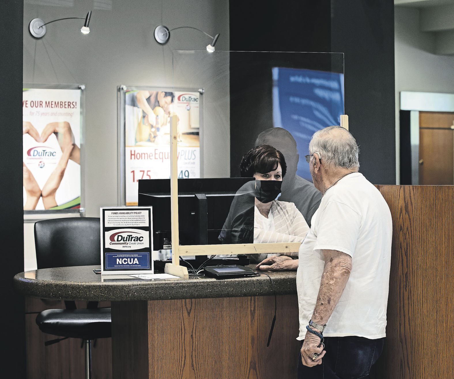 Customer Ron Holdridge talks with teller Melissa Steuer at the main DuTrac Community Credit Union branch on Asbury Road in Dubuque. The institution began in an office at the John Deere Dubuque Works plant. Today, it serves members in numerous counties.    PHOTO CREDIT: Stephen Gassman