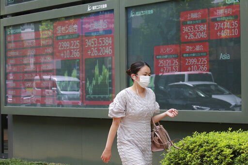 A woman walks by an electronic stock board of a securities firm in Tokyo. Asian shares rose today as investor sentiment received a big boost from the rally last week on Wall Street. Stocks are opening higher on Wall Street led by gains in a broad range of technology, financial and health care companies.    PHOTO CREDIT: Koji Sasahara