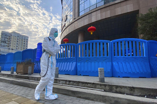 FILE - In this file photo dated Saturday, Feb. 6, 2021, a worker in protectively overalls and carrying disinfecting equipment walks outside the Wuhan Central Hospital where Li Wenliang, the whistleblower doctor who sounded the alarm and was reprimanded by local police for it in the early days of Wuhan