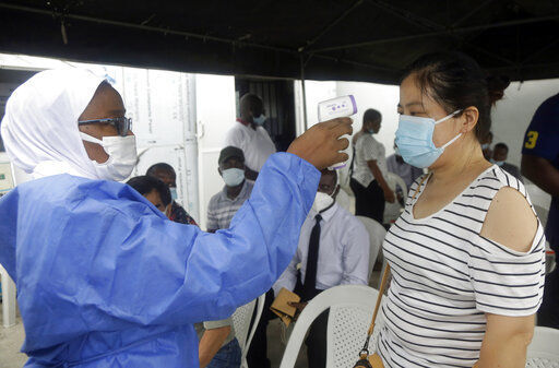 A nurse in protective gear takes the temperature of a woman waiting to take the Moderna coronavirus vaccine at the health center in Lagos, Nigeria Wednesday, Aug. 25, 2021. Nigeria has begun the second rollout of COVID-19 vaccines as it aims to protect its population of more than 200 million amid an infection surge in a third wave of the pandemic. (AP Photo/Sunday Alamba)    PHOTO CREDIT: Sunday Alamba