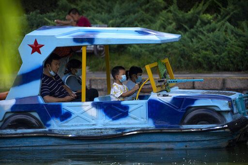 Children wearing face masks to help protect against COVID-19 ride in a boat decorated like a military vehicle at a public park in Beijing, Wednesday, Aug. 25, 2021. (AP Photo/Mark Schiefelbein)    PHOTO CREDIT: Mark Schiefelbein