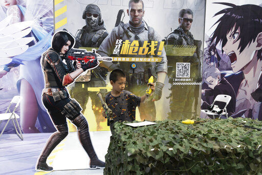 A child plays with a toy gun during a promotion for online games in Beijing on Saturday. China is banning children from playing online games for more than three hours a week, the harshest restriction so far on the game industry as Chinese regulators continue cracking down on the technology sector.    PHOTO CREDIT: Ng Han Guan