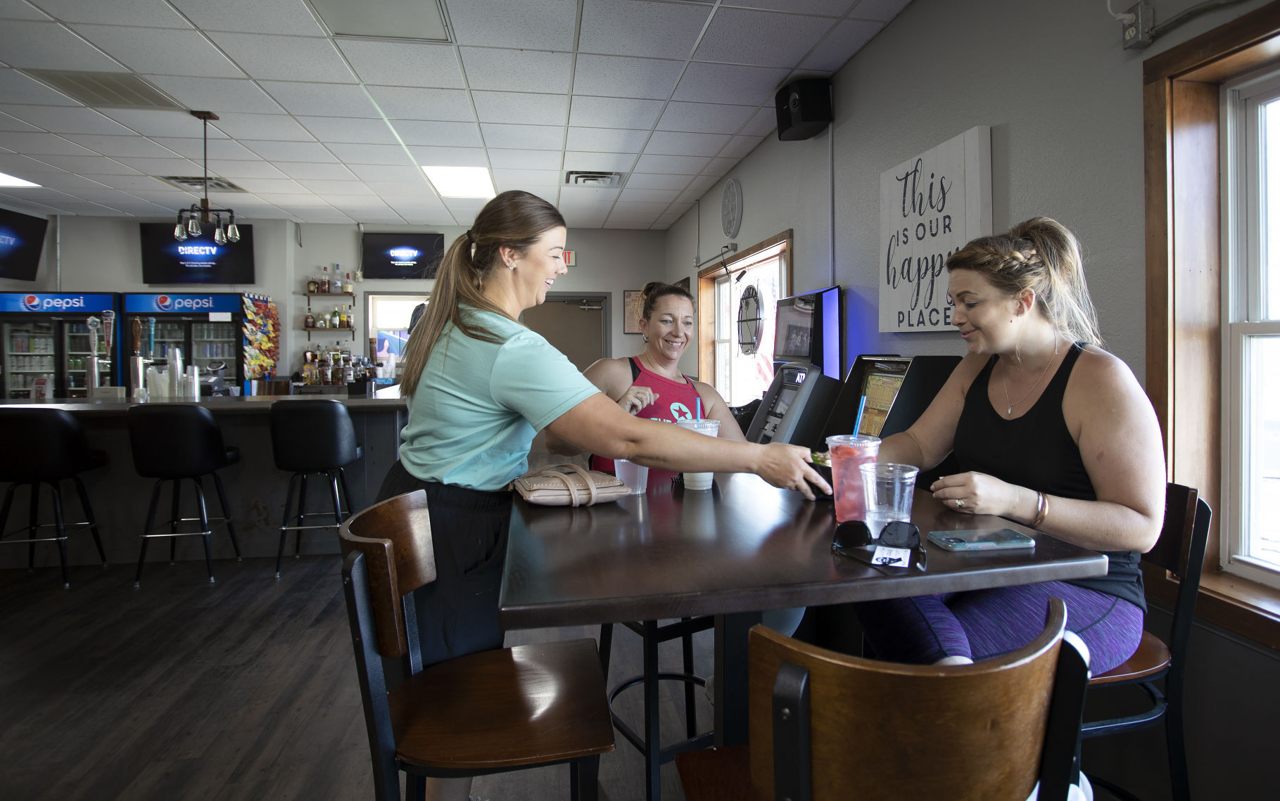 Lindsie Wessels (left) serves lunch to Abby Helle and Jess Goedken at Locals Bar & Coffee Shop in Epworth, Iowa, on Monday.    PHOTO CREDIT: Stephen Gassman