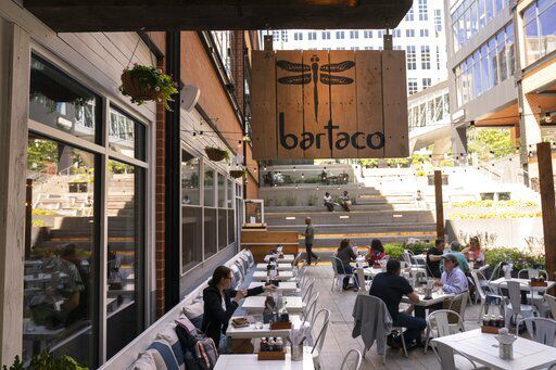 Patrons eat on the patio at Bartaco in Arlington, Va., on Thursday, Sept. 2, 2021. The restaurant uses an automated app for ordering and payments, accessed via a barcode attached to the table, and instead of servers they use "food runners" to get the orders to the tables. (AP Photo/Jacquelyn Martin)    PHOTO CREDIT: Jacquelyn Martin