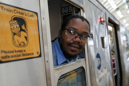 Desmond Hill, a vaccinated MTA conductor, checks the platform for late riders attempting to board the train as he works the N subway line from Brooklyn