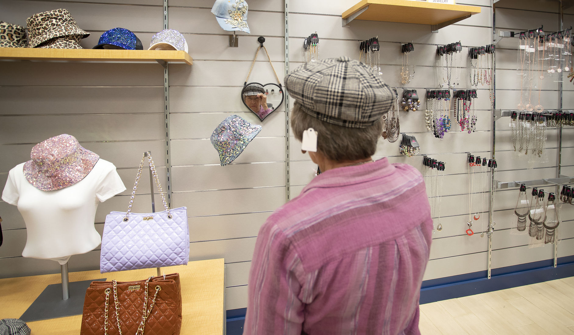 Customer Marge Cummer, of Dubuque, tries on a new hat at Glamvaganza, a new store recently opened at Kennedy Mall in Dubuque.    PHOTO CREDIT: Stephen Gassman
