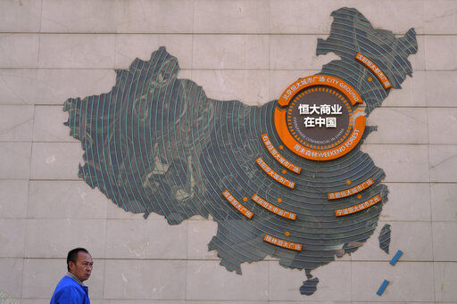 A custodian stands near a map showing Evergrande development projects in China on a wall in an Evergrande city plaza in Beijing today. Global investors are watching nervously as the Evergrande Group, one of China