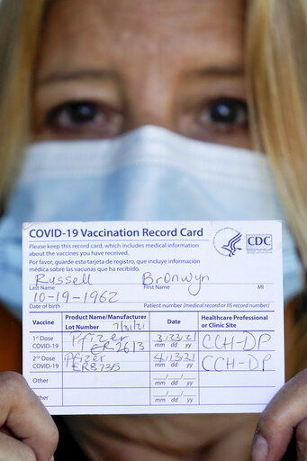 In this Monday, Sept. 27, 2021, photo Bronwyn Russell holds her COVID-19 vaccination record card as she poses for a photo at her home in Des Plaines, Ill. Russell wears a mask anytime she leaves her Illinois home. “I’m worried. I don’t want to get sick,” says Russell. (AP Photo/Nam Y. Huh)    PHOTO CREDIT: Nam Y. Huh