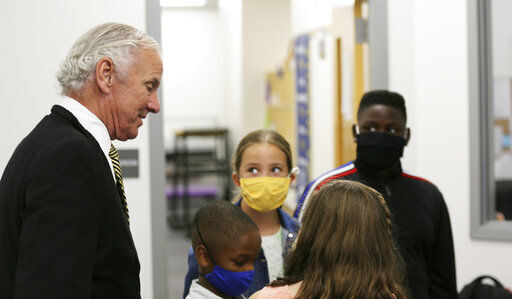 FILE - Camden Elementary School students in masks listen as South Carolina Gov. Henry McMaster talks to them on Wednesday, Sept. 15, 2021, in Camden, S.C. A federal judge Tuesday, Sept. 28 suspended South Carolina from enforcing a rule that banned school districts from requiring masks for students. Parents of disabled children, helped by the American Civil Liberties Union, sued the state saying the ban discriminated against medically vulnerable students by keeping them out of public schools as the COVID-19 pandemic continues. The mask ban has been forcefully backed by McMaster and GOP lawmakers who said parents should decide whether students wear masks, not school officials. (AP Photo/Jeffrey Collins, File)    PHOTO CREDIT: Jeffrey Collins