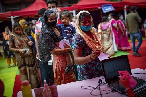 People wait to register themselves to receive vaccine for COVID-19 during an inoculation drive in New Delhi, India, Wednesday, Sept. 29, 2021. India, the world’s largest vaccine producer, will resume exports and donations of surplus coronavirus vaccines in October after halting them during a devastating surge in domestic infections in April. (AP Photo/Altaf Qadri)    PHOTO CREDIT: Altaf Qadri