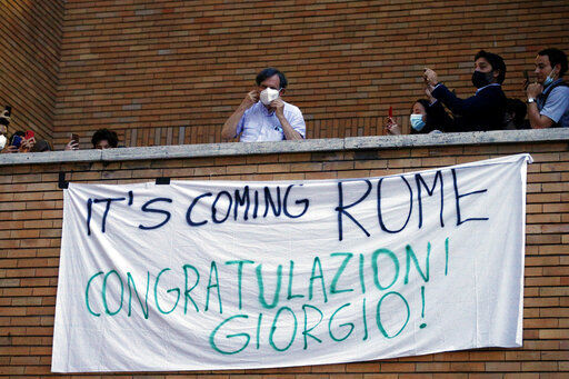Italian physicist Giorgio Parisi stands on a balcony over a banner reading " It