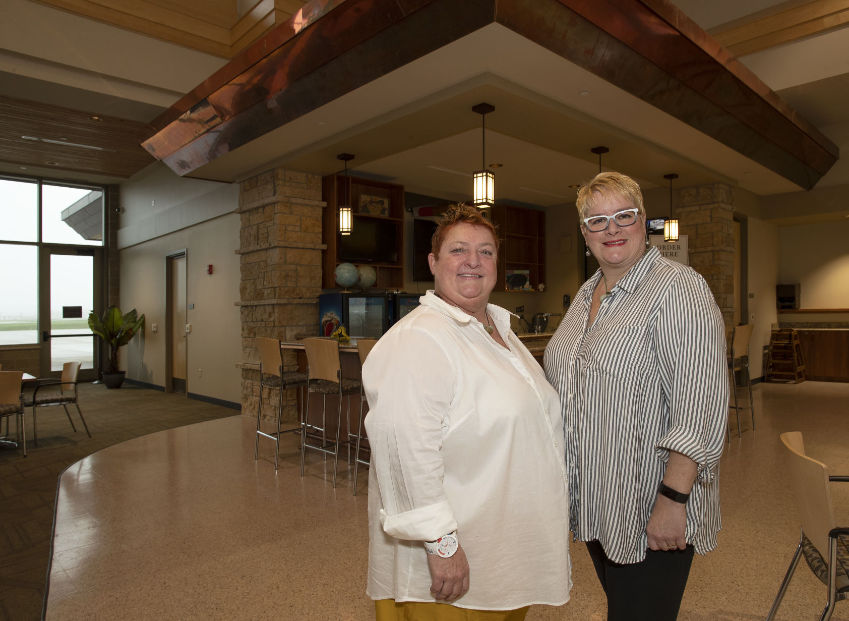 Business owners Carolyn (left) and Angela Linton-Canfield stand in front of All on Board with Life’s a Feast, which soon will open at Dubuque Regional Airport.    PHOTO CREDIT: Stephen Gassman