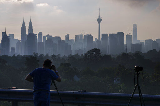 A photographer takes pictures of morning city view of Kuala Lumpur, Malaysia, Monday, Oct. 11, 2021. State borders reopened after a months-long ban in a move that is expected to rejuvenate tourism and the economy. With over 90% of the country