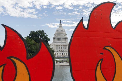 In this Oct. 15, 2021, photo, the U.S. Capitol is seen between cardboard cutouts of flames during a climate change protest near the U.S. Capitol in Washington. President Joe Biden heads to a vital U.N. climate change summit at a time when a majority of Americans regard the deteriorating climate as a problem of high importance to them. That