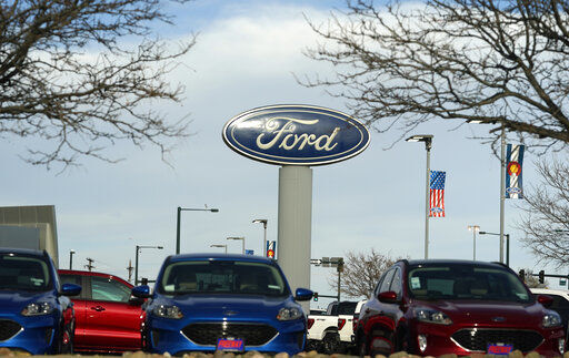 In this Sunday, April 25, 2021, photograph, the blue oval logo of Ford Motor Company is shown over a row of unsold 2021 Escapes at a dealership in east Denver. The global computer chip shortage cut into third-quarter profits at both Ford and crosstown rival General Motors, with both companies having to temporarily close factories, pinching supplies on dealer lots, according to results announced Wednesday, Oct. 27. (AP Photo/David Zalubowski)    PHOTO CREDIT: David Zalubowski