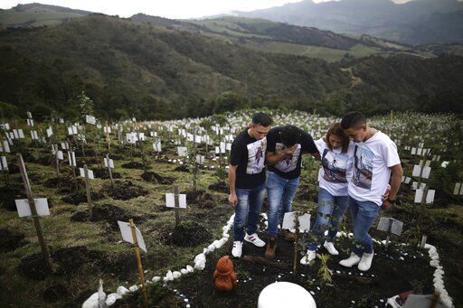 Relatives of Luis Enrique Rodriguez, who died of COVID-19, visit where he was buried on a hill at the El Pajonal de Cogua Natural Reserve, in Cogua, north of Bogota, Colombia. The global death toll from COVID-19 topped 5 million today, less than two years into a crisis that has not only devastated poor countries but also humbled wealthy ones with first-rate health care systems.    PHOTO CREDIT: Ivan Valencia