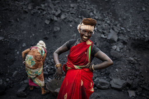 An Indian laborer smiles as she takes a break from loading coal into a truck in Dhanbad, an eastern Indian city in Jharkhand state. Efforts to fight climate change are being held back in part because coal, the biggest single source of climate-changing gases, provides cheap electricity and supports millions of jobs.     PHOTO CREDIT: Altaf Qadri