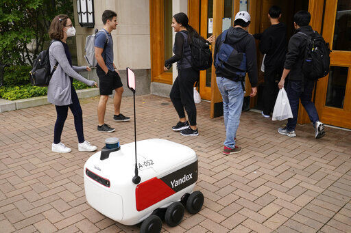 A food delivery robot stops outside a building in Ann Arbor, Mich. Robot food delivery is no longer the stuff of science fiction. Hundreds of little robots - knee-high and able to hold around four large pizzas - are navigating college campuses and even some city sidewalks in the U.S., the U.K. and elsewhere. While robots were being tested in limited numbers before the coronavirus hit, the companies building them say pandemic-related labor shortages and a growing preference for contactless delivery have accelerated their deployment.     PHOTO CREDIT: Carlos Osorio