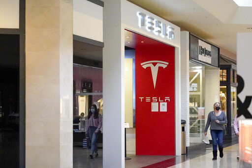 This photo made Wednesday, Feb. 24, 2021, shows people walking by the entrance to a Tesla store at a shopping mall in Pittsburgh. Tesla shares slumped about 5% in premarket trading after its CEO Elon Musk said he would sell 10% of his holdings — about $20 billion worth — in the electric car maker based on the results of a poll he conducted on Twitter over the weekend. (AP Photo/Keith Srakocic)    PHOTO CREDIT: Keith Srakocic