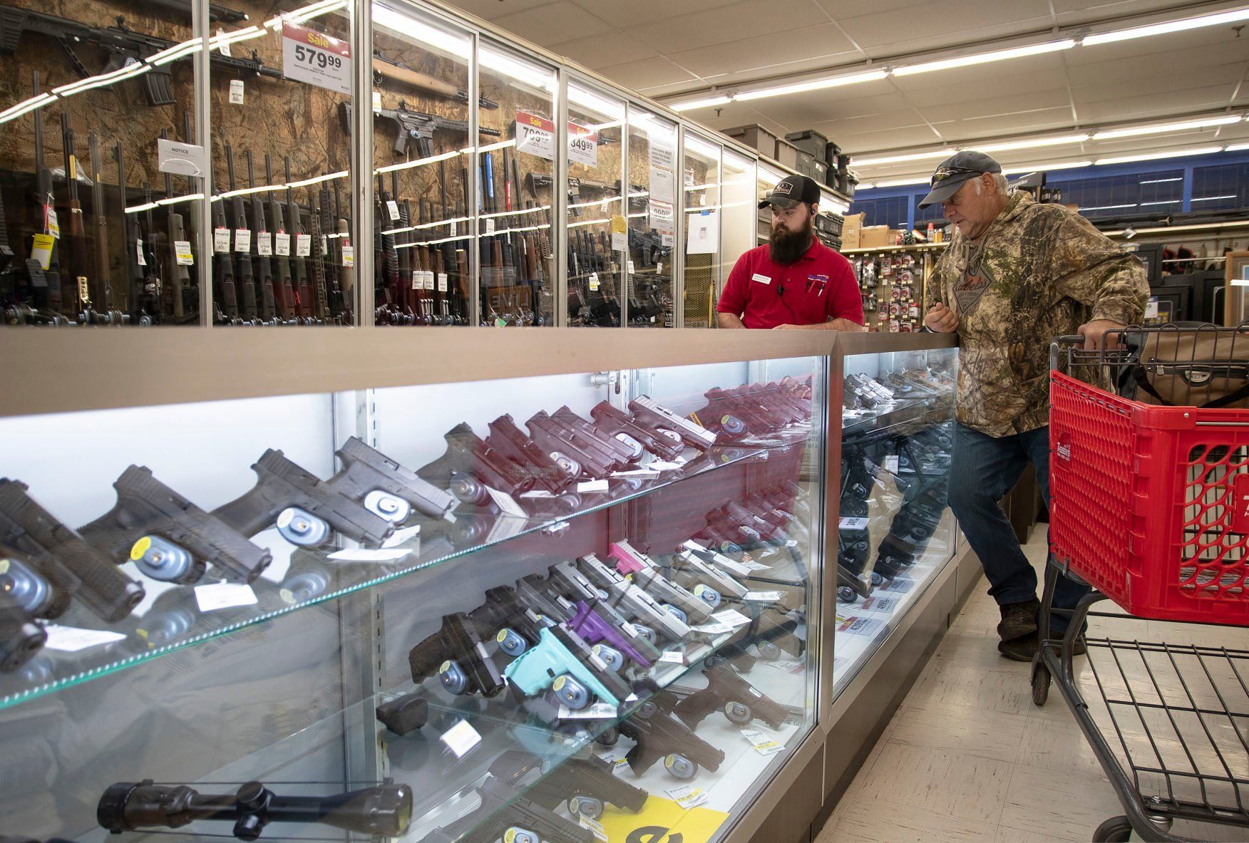 Theisen’s employee Logan Payne discusses guns with Kevin Hall, of Platteville, Wis., at the Dubuque store Thursday.    PHOTO CREDIT: Stephen Gassman