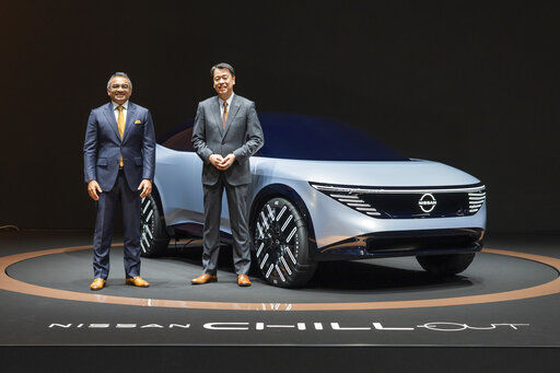 Nissan Motor Co. Chief Executive Makoto Uchida (right), and COO Ashwani Gupta pose with a Nissan Chill-Out concept car on Nov. 27, 2021. Nissan said today that it is investing 2 trillion yen ($17.6 billion) over the next five years and developing a cheaper, more powerful battery to boost its electric vehicle lineup.     PHOTO CREDIT: Nissan Motor Co. via AP