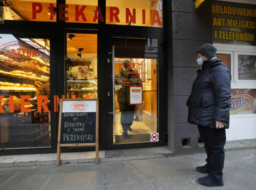 A customer wearing a face mask prepares to leave a bakery, in Warsaw, Poland, on Friday Nov. 26, 2021. Poland is facing skyrocketing COVID-19 infections and deaths but for now the government does not plan any new lockdowns or other restrictions. (AP Photo/Czarek Sokolowski)    PHOTO CREDIT: Czarek Sokolowski