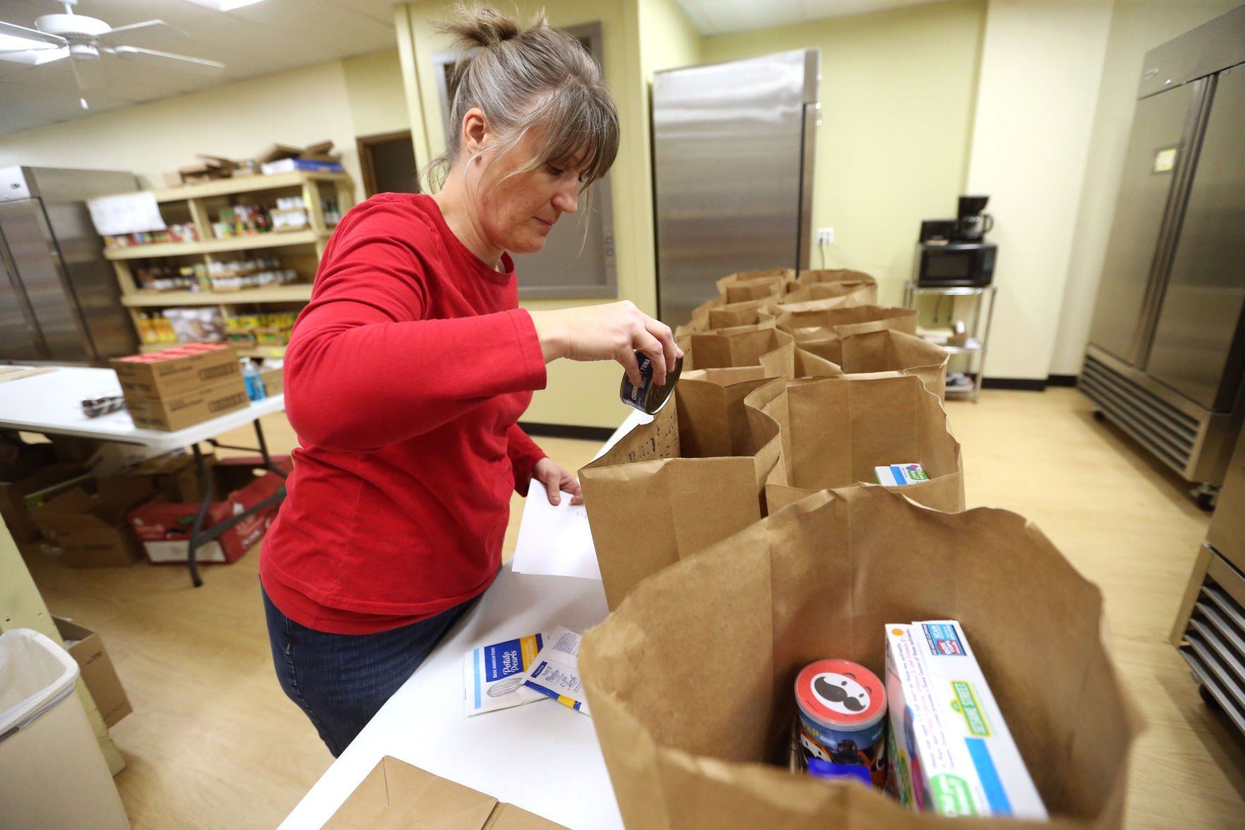 Becca Brosius, a part-time employee with the Dubuque Food Pantry, fills bags at the pantry on Tuesday.    PHOTO CREDIT: JESSICA REILLY