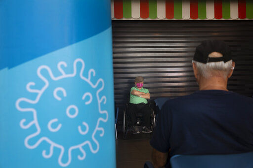 FILE - Men are seated after receiving the a third Pfizer-BioNTech COVID-19 vaccine at a coronavirus vaccination center in Tel Aviv, Israel, Tuesday, Aug. 10, 2021. The coronavirus
