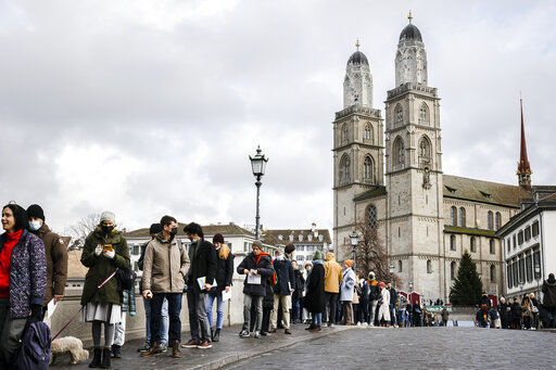 FILE - People queue from the Muenster Bridge to the Zurich City Hall to cast their ballot at the City Hall polling station to vote in a COVID-19 referendum, in Zurich, Switzerland, Sunday, Nov. 28, 2021. The coronavirus