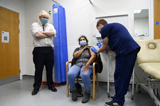 FILE - British Prime Minister Boris Johnson, left, watches as a patient receives a COVID-19 vaccine during his visit to the Lordship Lane Primary care center where he met staff and people receiving their booster vaccines, in London, Tuesday, Nov. 30, 2021. The coronavirus