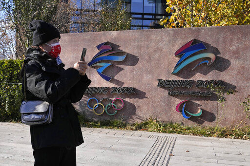 A visitor to the Shougang Park walks past the logos for the Beijing Winter Olympics and Paralympics in Beijing, China, Tuesday, Nov. 9, 2021. China on Monday, Dec. 6, 2021 threatened to take "firm countermeasures" if the U.S. proceeds with a diplomatic boycott of February