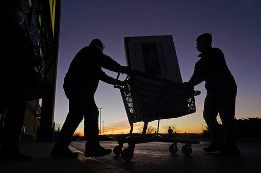People transport a television to their car after shopping during a Black Friday sale at a Best Buy store in Overland Park, Kan. Retailers overall are expecting record-breaking sales for the holiday shopping season, but low-income customers are struggling as they bear the brunt of the highest inflation in 39 years.     PHOTO CREDIT: Charlie Riedel
