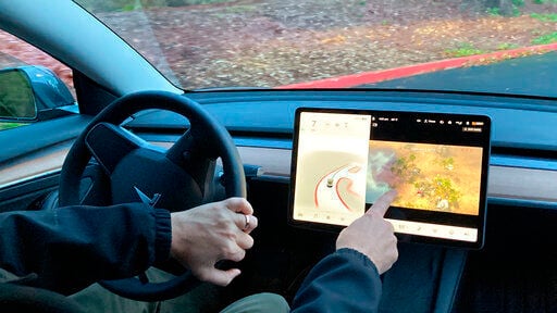 Vince Patton, a new Tesla owner, demonstrates on a closed course in Portland, Ore., how he can play video games on the vehicle