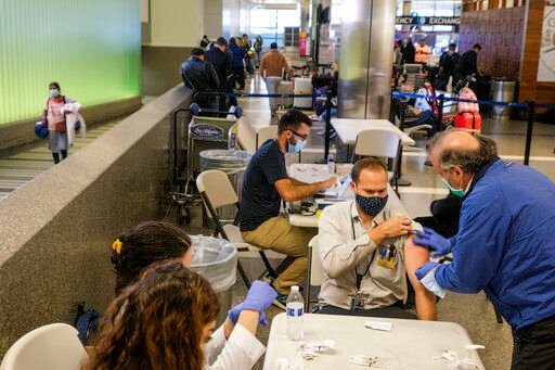 FILE - A traveler is vaccinated at the Los Angeles International Airport in Los Angeles, Wednesday Dec. 22, 2021. More than a year after the vaccine was rolled out, new cases of COVID-19 in the U.S. have soared to the highest level on record at over 265,000 per day on average, a surge driven largely by the highly contagious omicron variant. (AP Photo/Ringo H.W. Chiu, File)    PHOTO CREDIT: Ringo H.W. Chiu