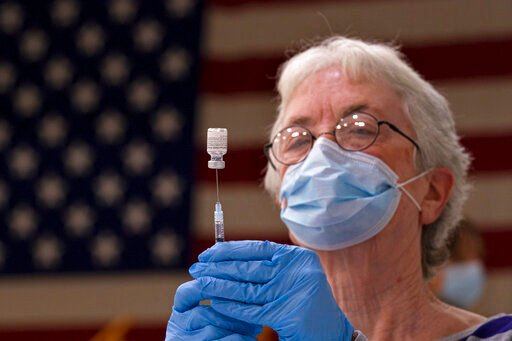 FILE - Pam Hetherly fills a syringe with COVID-19 vaccine at a clinic at the Augusta Armory, Dec. 21, 2021, in Augusta, Maine. More than a year after the vaccine was rolled out, new cases of COVID-19 in the U.S. have soared to the highest level on record at over 265,000 per day on average, a surge driven largely by the highly contagious omicron variant. (AP Photo/Robert F. Bukaty, File)    PHOTO CREDIT: Robert F. Bukaty