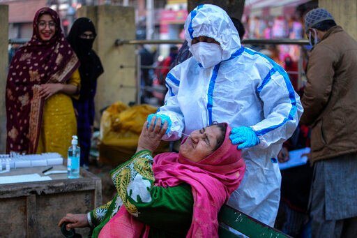 A health worker collects a swab sample of a woman to test for COVID-19 at a market in Jammu, India, Wednesday, Dec.29, 2021. In India, which has been getting back to normal after a devastating COVID-19 outbreak earlier this year, omicron is once again raising fears, with more than 700 cases reported in the country of nearly 1.4 billion people. (AP Photo/Channi Anand)    PHOTO CREDIT: Channi Anand