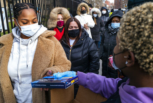 FILE - People line up and receive test kits to detect COVID-19 as they are distributed in New York on Dec. 23, 2021. More than a year after the vaccine was rolled out, new cases of COVID-19 in the U.S. have soared to their highest level on record at over 265,000 per day on average, a surge driven largely by the highly contagious omicron variant. (AP Photo/Craig Ruttle, File)    PHOTO CREDIT: Craig Ruttle