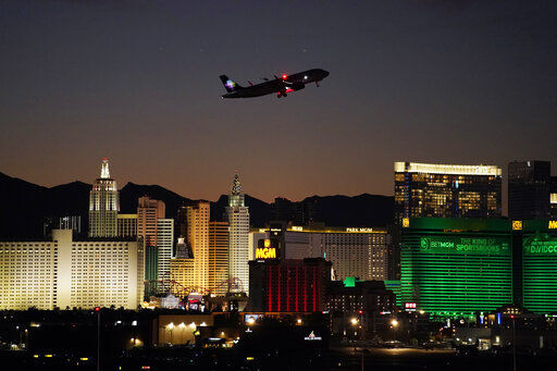 FILE - A plane takes off from McCarran International Airport near casinos along the Las Vegas Strip, Wednesday, Sept. 29, 2021, in Las Vegas. Nevada casinos set a record in November, reporting a ninth straight month of $1 billion or more in house winnings in a sign that business in the nation