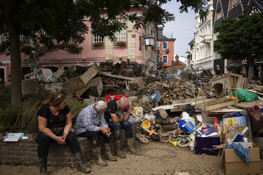 FILE - People rest from cleaning up the debris of the flood disaster in Bad Neuenahr-Ahrweiler, Germany, on July 19, 2021. Cybersecurity and space are emerging risks to the global economy, adding to existing challenges posed by climate change and the coronavirus pandemic, the World Economic Forum said in a report Tuesday, Jan. 11, 2022. (AP Photo/Bram Janssen)    PHOTO CREDIT: Bram Janssen