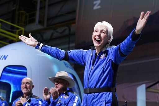 FILE - Wally Funk, right, describes their flight experience as Mark Bezos, left, and Jeff Bezos, left, center, founder of Amazon and space tourism company Blue Origin, applaud from the spaceport near Van Horn, Texas, on July 20, 2021. Cybersecurity and space are emerging risks to the global economy, adding to existing challenges posed by climate change and the coronavirus pandemic, the World Economic Forum said in a report Tuesday, Jan. 11, 2022. (AP Photo/Tony Gutierrez)    PHOTO CREDIT: Tony Gutierrez