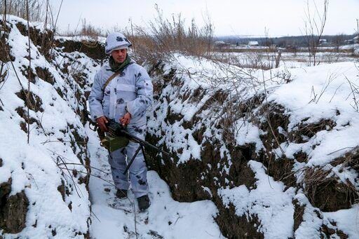 A serviceman stands holding his machine-gun in a trench on the territory controlled by pro-Russian militants at frontline with Ukrainian government forces in Slavyanoserbsk, Luhansk region, eastern Ukraine, Tuesday, Jan. 25, 2022. Ukraine
